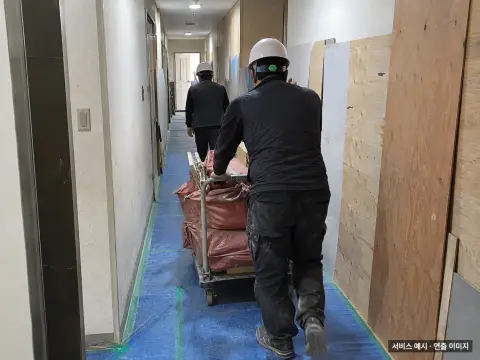 보양된 복도에서 철거 폐기물을 운반하는 작업자