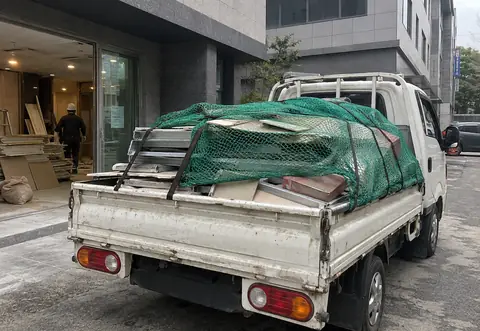 철거 자재가 소형 트럭에 덮개와 함께 적재된 장면