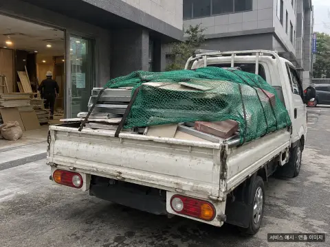 철거 자재가 소형 트럭에 덮개와 함께 적재된 장면