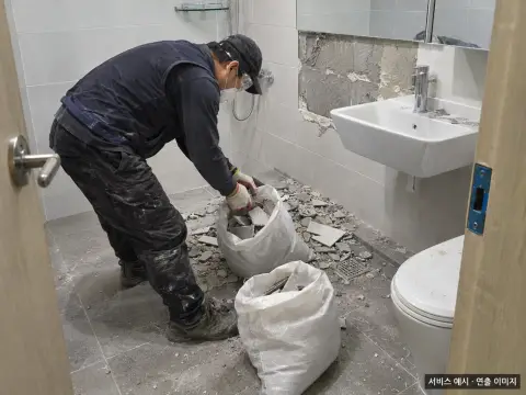 욕실 철거 폐기물을 마대에 담아 정리하는 작업
